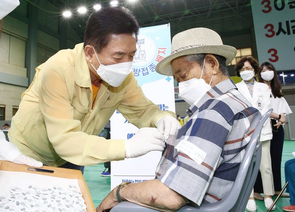 화순군 80% 예방접종 완료 : 화순군이 코로나19 백신 2차 접종률 80%를 돌파했다. 사진은 지난 7월 구충곤(사진 왼쪽) 화순군수가 예방접종 완료 어르신에게 백신 접종 배지를 달아주는 모습.