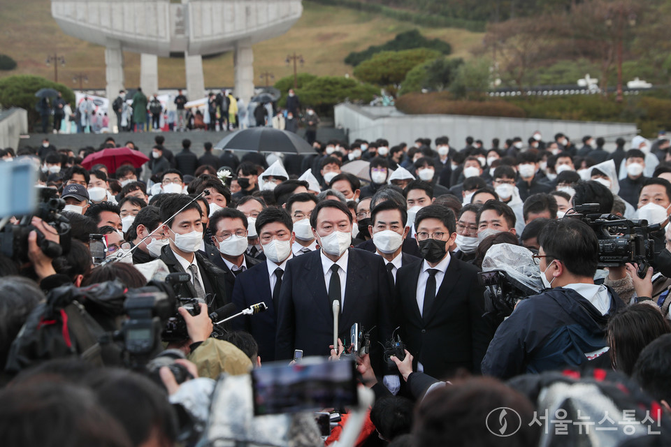 국민의힘 윤석열 대선후보가 10일 광주 북구 5·18 민주묘지에서 항의하는 시민들에게 막혀 추모탑에 분향하지 못하고 비를 맞으며 광장에서 묵념으로 참배했다. 