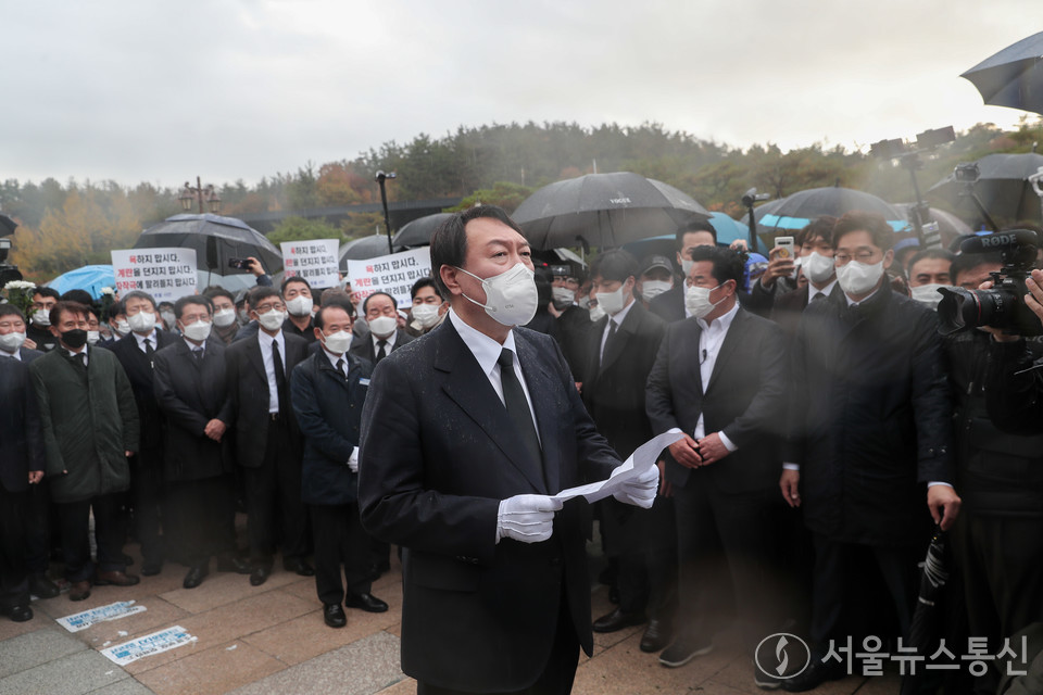 국민의힘 윤석열 대선후보가 10일 광주 북구 5·18 민주묘지에서 항의하는 시민들에게 막혀 추모탑에 분향하지 못하고 비를 맞으며 광장에서 묵념으로 참배했다. 