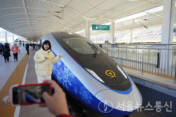 한 기자가 6일 허베이(河北)성 장자커우(張家口)시 타이쯔청(太子城)역에서 G9981편 베이징 동계올림픽 테마 고속열차를 배경으로 포즈를 취하고 있다. / 신화통신 제공
