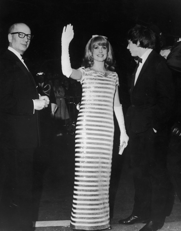 프랑스 여배우 카트린 드뇌브가 1966년 칸 영화제에서 흰 장갑과 스팽글 장식으로 팬들을 맞이하고 있다/CNN