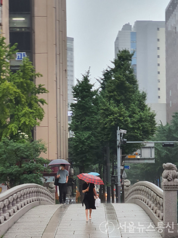 30일 오전 서울 청계광장 모전교를 시민들이 우산을 쓴 채 건너고 있다. / 사진=송혜숙 기자