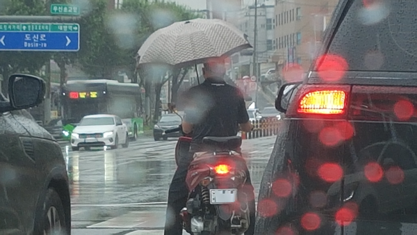오늘(21일) 전국에 장맛비가 내리는 가운데 출근길 한 오토바이 운전자가 비를 피하기 위해서 신호대기 중에 우산을 쓰고 있다. 2022.7.21/사진 = 프리랜서 황수연 기자