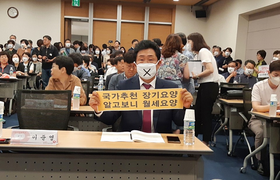 권태엽 한국노인복지중앙회장(사진 가운데)이 지난 19일 서울 중구 대한상공회의소에서 열린 '신 노년층 요양시설 서비스 활성화 방안 연구 관련 공청회'에서 '국가추천 장기요양, 알고보니 월세요양'이라는 팻말을 들고 침묵시위에 들어갔다. (한국노인복지중앙회 사진제공)