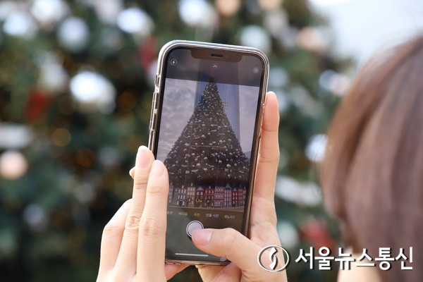 27일 서울 잠실에 장식된 크리스마스 트리를 한 시민이 스마트폰으로 촬영하고 있다. (2023.11.27) / 사진 = 서울뉴스통신 이성현 기자