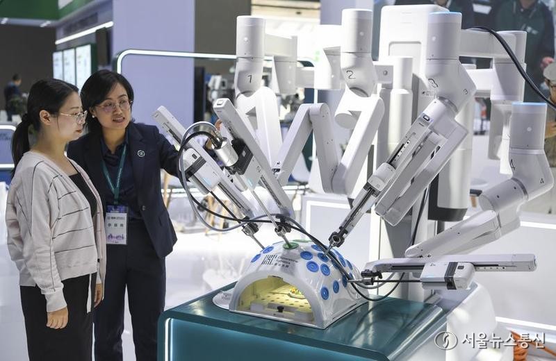 29일 '2024년 중국의학장비전시회'에서 수술용 로봇을 구경하는 관람객. (사진/신화통신)
