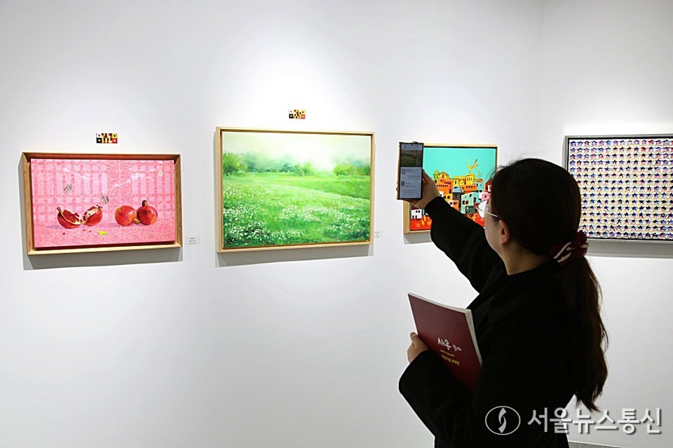 자연의 감정을 화폭에 담아내는 강수영 작가가 하남시 중심에 새롭게 개관한 ‘사우 갤러리’의 개관 초대전에 참여했다. 사진은 한 관람객이 그림에 붙은 바코드로 그림의 정보를 확인하는 모습 (2025,04.05) / 사진 = 서울뉴스통신 이성현 기자