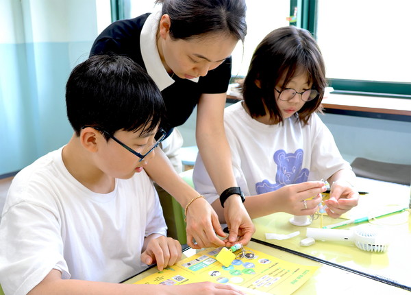 [참고사진①] 일일 선생님이 된 LG화학 임직원이 아이들과 폐플라스틱으로 키링 만들기를 체험을 하고 있다