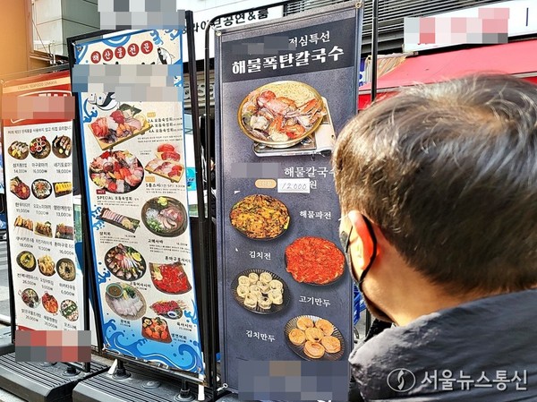 정부가 내년도 예산안에 ‘직장인 든든한 한끼’ 시범사업을 새로 포함시키면서 정치권과 여론에서 찬반 논란이 일고 있다. 사진은 13일 강남역 먹자골목에서 한 직장인이 한 식당의 메뉴를 살펴보고 있다. (2024.12.13) / 사진 = 서울뉴스통신 이성현 기자 