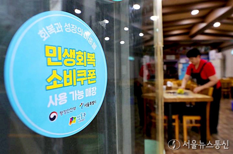 서울 성동구 한 매장에서 자영업자가 손님맞이 준비를 하고 있는 가운데 '소비쿠폰 사용 가능' 안내 스티커가 부착되어 있다. (2025.07.17) / 사진= 성동구 제공