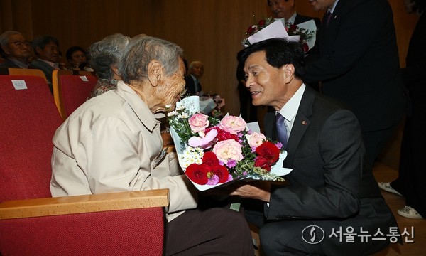 안병구 밀양시장이 제29회 노인의 날 기념행사에서 표창 수상자에게 축하 꽃다발을 전달하고 있다.