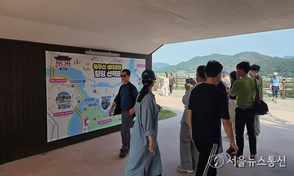 용두산 생태공원 힐링 산책코스 안내도 앞에서 시민들이 산책 코스를 살펴보고 있는 모습